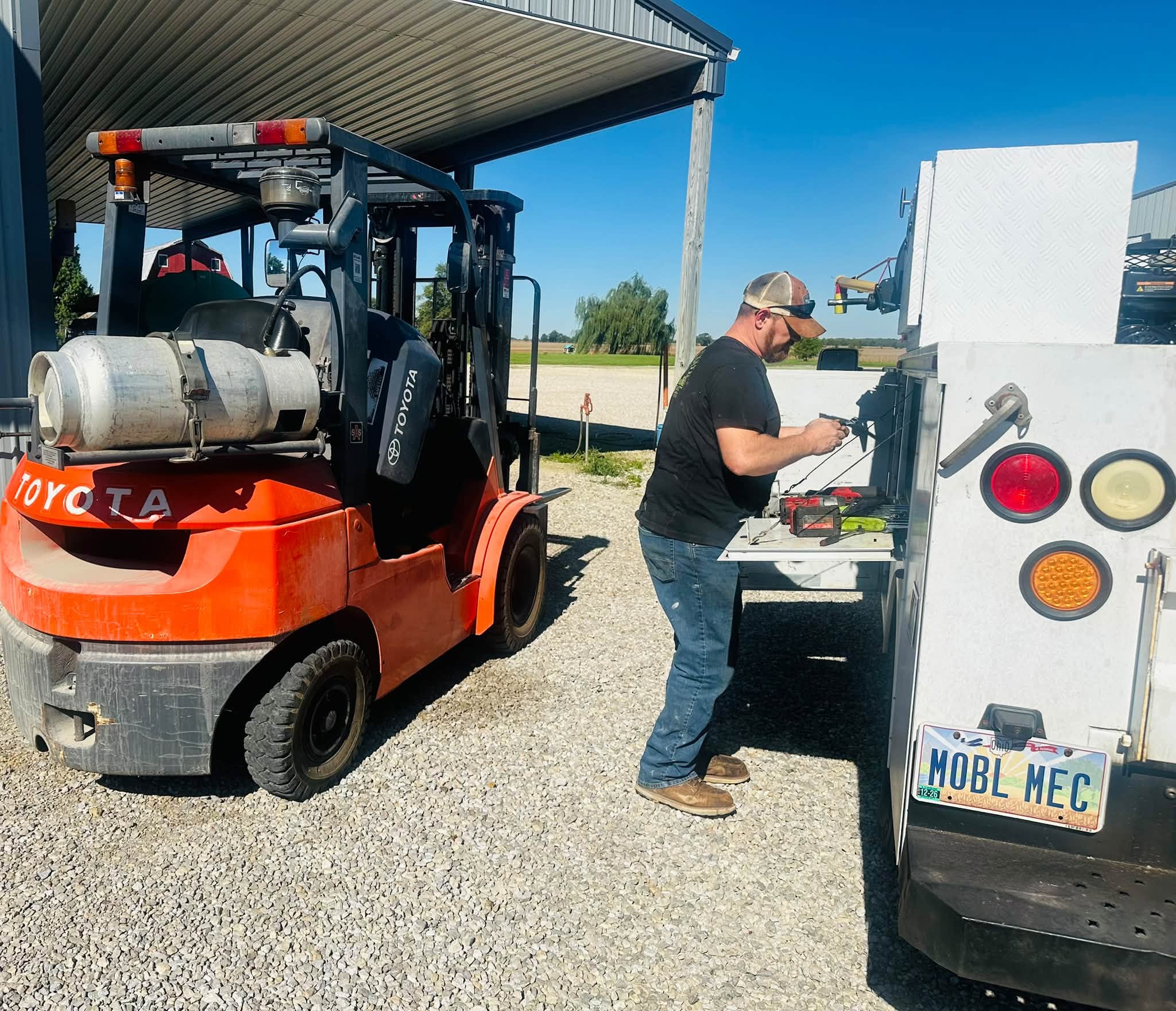Paul working beside a forklift and his mobile service truck