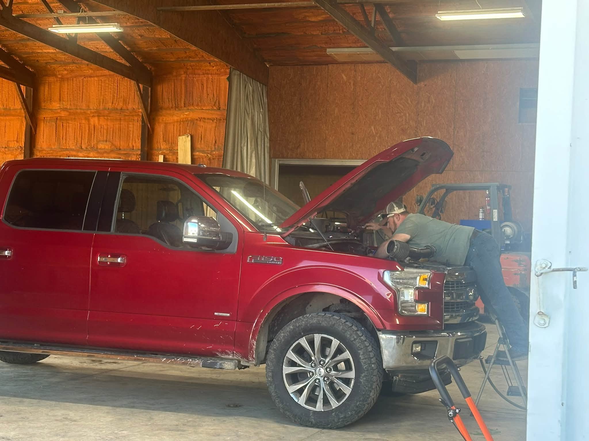Paul working under the hood of a red pickup
